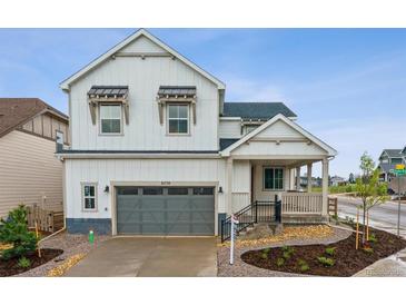 Charming two-story home boasts a gray garage, landscaped front yard, and inviting covered porch at 8230 Snake River St, Littleton, CO 80125