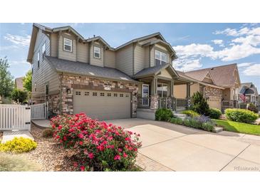 Charming two-story home featuring stone accents, a covered porch, and a well-manicured front yard with colorful flower beds at 190 Olympia Ave, Longmont, CO 80504