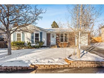 Brick ranch home with attached garage and snow-covered yard at 10401 W Lehigh Ave, Denver, CO 80235