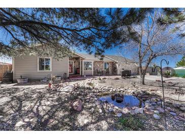 Charming home exterior with stone accents, a lovely pond, and mature landscaping at 7605 Shenandoah Dr, Elizabeth, CO 80107