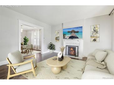 Bright living room boasts fireplace, hardwood floors, neutral paint, and light filled dining room at 142 N Logan St, Denver, CO 80203
