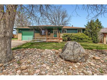 Ranch home featuring a well-kept lawn, rock garden, attached garage, and a front porch at 13621 E Center Ave, Aurora, CO 80012