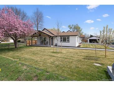 Charming one-story home with white siding, a covered porch, and a well-manicured lawn at 20 S Harlan St, Lakewood, CO 80226