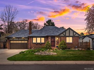 Charming brick home featuring an attached garage and a well-manicured front yard at dusk at 2535 Leyden St, Denver, CO 80207