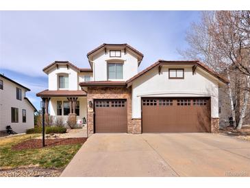 Stunning two-story stucco home with a three-car garage, stone accents, and well-manicured landscaping at 9591 Sunset Hill Dr, Lone Tree, CO 80124