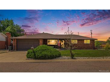 Charming brick home featuring a manicured lawn, mature landscaping, and attached garage, creating a welcoming curb appeal at 7777 Newman St, Arvada, CO 80005