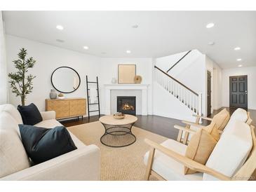 Bright living room with fireplace, modern furniture, dark wood floors, and staircase at 3438 Cade Ct, Castle Rock, CO 80104