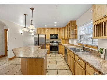 Bright kitchen features an island, stainless steel appliances, natural wood cabinetry, and tile flooring at 205 Beech St, Hudson, CO 80642