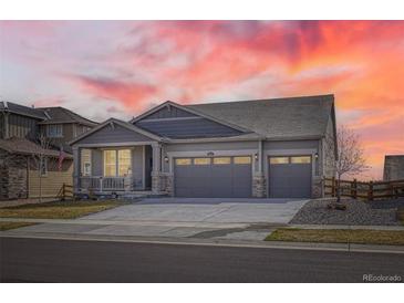 Charming home with a three-car garage and covered porch, showcasing beautiful landscaping at sunset at 1832 Marlowe Cir, Erie, CO 80516