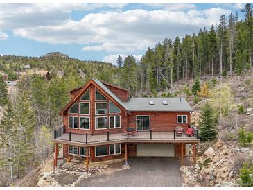 Stunning two-story home featuring a large deck and expansive windows to admire the surrounding mountain forest at 800 Highway 72, Golden, CO 80403