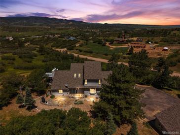 Stunning aerial view of a home with mountain views and lush landscaping at twilight at 2357 Oak Ridge Rd, Sedalia, CO 80135