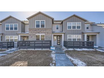 Modern two-story townhome with gray siding, brick accents, and a private fenced yard at 2571 W 69Th Pl, Denver, CO 80221