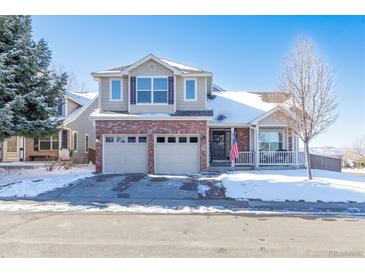 Two-story brick home with a two-car garage and a snowy front yard at 9705 Spring Hill St, Highlands Ranch, CO 80129