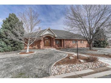 A beautiful single-story brick home with a well-manicured lawn and mature trees lining the property at 14581 E Oberlin Pl, Aurora, CO 80014