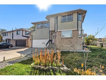 Two-story home featuring mixed siding, brick, attached two-car garage, lawn, and flower bed on a sunny day at 6500 E Asbury Ave, Denver, CO 80224