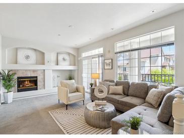 Bright living room with a modern fireplace, grey sofa, and access to a balcony through sliding glass doors at 12711 Colorado Blvd # H804, Thornton, CO 80241
