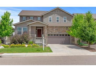 Two-story home featuring stone accents, a covered entry, and a two-car garage at 6185 Saddle Bow Ave, Parker, CO 80134