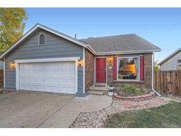 Gray and brick ranch home with a two-car garage and red front door at 7814 Club Crest Dr, Arvada, CO 80005