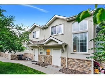 Charming townhome featuring stone accents, a well-maintained lawn, and a welcoming entrance at 2143 Coronado N Pkwy # C, Denver, CO 80229