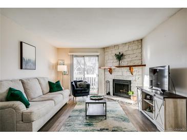 Inviting living room with stone fireplace, wood floors, and sliding glass door to the outside at 8555 S Fairmount Dr # 107, Denver, CO 80247