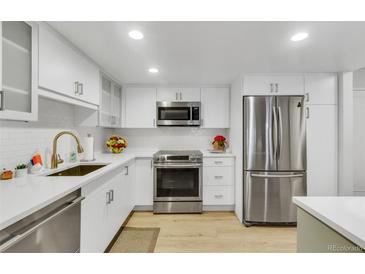 This is a kitchen with stainless steel appliances and bright white cabinets at 13631 E Marina Dr # 105, Aurora, CO 80014