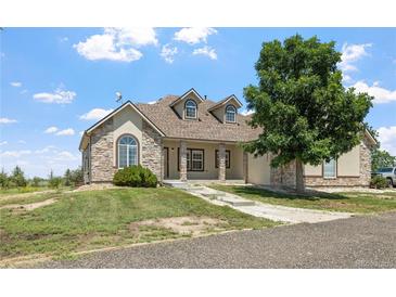 Charming stone and stucco home with a well-manicured lawn and inviting front porch at 34771 E 153Rd Ct, Hudson, CO 80642