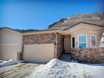 Tan two-story home with stone accents and a two-car garage, nestled in a snowy landscape at 6945 Fargo Trl, Littleton, CO 80125