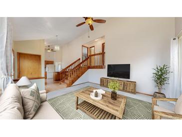 Bright living room featuring a ceiling fan, hardwood floors, and staircase leading to the upper level at 412 N 10Th Ave, Brighton, CO 80601