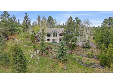 Charming home nestled among trees on a landscaped hillside featuring a stone retaining wall at 787 W Meadow Rd, Evergreen, CO 80439