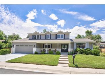 Two-story home featuring a spacious front yard, covered porch, and attached garage at 3843 S Quince St, Denver, CO 80237