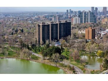 Stunning aerial view of Denver apartment buildings with lake and city skyline, showing surrounding park and walking trails at 460 S Marion Pkwy # 1351, Denver, CO 80209