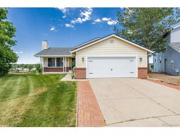 Charming single-Gathering home featuring a manicured lawn and an attached two-car garage with white doors at 551 Snowy Owl Pl, Highlands Ranch, CO 80126