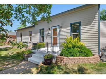 Tan house with green landscaping and a white porch at 2311 W 46Th Ave, Denver, CO 80211