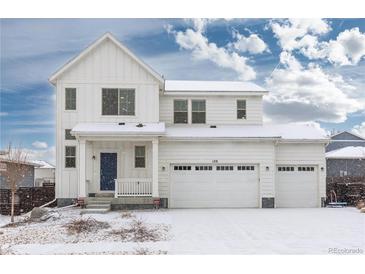 Inviting two-story home featuring a three-car garage, snow-covered yard, and charming front porch at 126 S Vandriver Way, Aurora, CO 80018