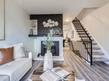 Bright living room boasts modern fireplace, contemporary decor, and beautiful staircase access to upper level at 17681 E Loyola Dr # E, Aurora, CO 80013