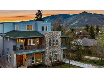 A modern, multi-story home with a stone facade and balconies offers stunning views of the surrounding mountains at sunset at 613 Iowa St, Golden, CO 80403