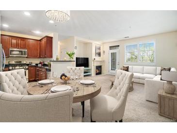Open-concept living space featuring a fireplace, dining area with chandelier, and modern kitchen with dark cabinets at 8039 Lee Dr # 2, Arvada, CO 80005