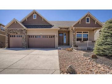 Charming home featuring a two-car garage, stone accents, covered front porch, and well-maintained landscaping at 1815 Avery Way, Castle Rock, CO 80109