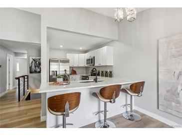 Bright modern kitchen featuring white cabinets, stainless steel appliances, and stylish bar seating at 19644 E Girard Dr, Aurora, CO 80013
