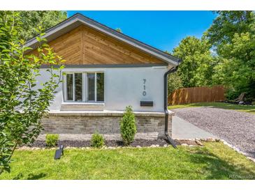 Charming home exterior featuring a manicured lawn, gray brick and white stucco and tasteful landscaping at 710 Raleigh St, Denver, CO 80204