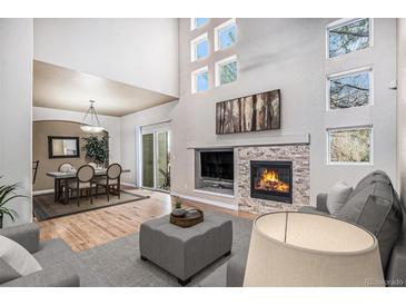 Bright living room with fireplace, hardwood floors, and dining area access at 6617 S Forest Way # E, Centennial, CO 80121