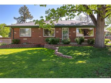 Charming brick home featuring a manicured front lawn, attractive landscaping, and mature trees at 4530 S Inca St, Englewood, CO 80110