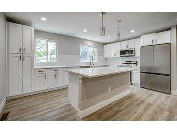 Bright kitchen features white cabinets, stainless steel appliances, and a large center island with a white countertop at 363 Lima St, Aurora, CO 80010