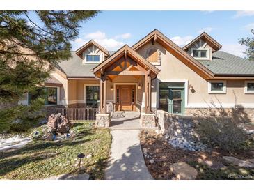 Inviting home featuring a beautiful wood porch, stone accents, and mature landscaping, creating great curb appeal at 7115 Parkwood Ln, Castle Pines, CO 80108