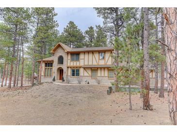 Stunning two-story Tudor-style home surrounded by mature trees and natural landscaping at 70 Long Bow Cir, Monument, CO 80132