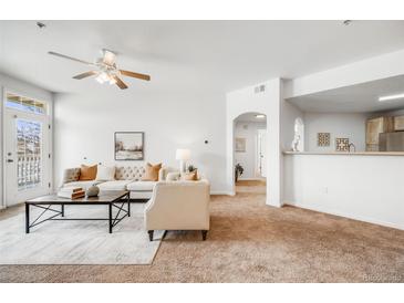 Bright and airy living room with plush seating, a ceiling fan, and access to the outdoors at 5726 N Genoa Way # 204, Aurora, CO 80019