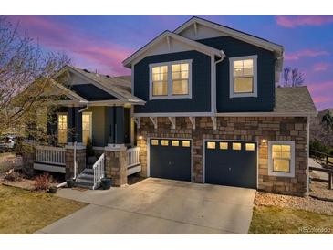 Charming two-story home featuring a stone facade, a covered porch, and a two-car garage at 2730 River View Dr, Broomfield, CO 80023