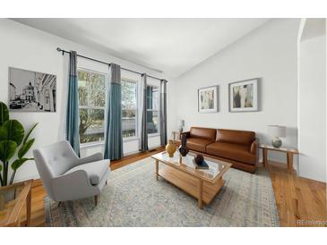 Bright living room with a leather sofa, area rug, and plenty of natural light from the large windows at 2730 River View Dr, Broomfield, CO 80023