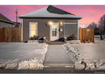 Charming exterior of home with neutral siding, covered in freshly fallen snow at sunset at 402 Harrison Ave, Fort Lupton, CO 80621