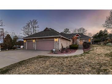 Charming single-Gathering home featuring a brick facade, three-car garage, and beautifully landscaped front yard at 7769 W 70Th Dr, Arvada, CO 80004